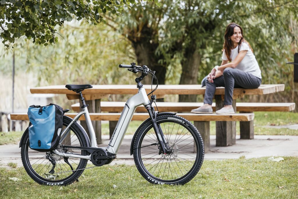 een vrouw rust uit bij een picknick bank met haar flyer elektrische fiets