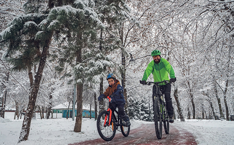 man en kind fietsen in de sneeuw op hun veilige fiets